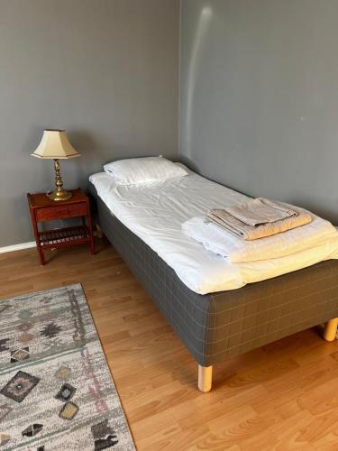 a bed in a room with a lamp and a table at Spacious house in cozy Kristdala in Kristdala