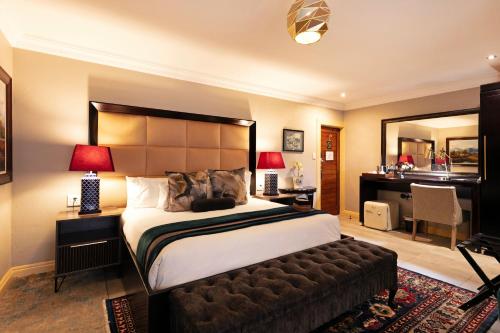 a bedroom with a bed and a desk and a mirror at Sasavona Boutique Hotel in Polokwane