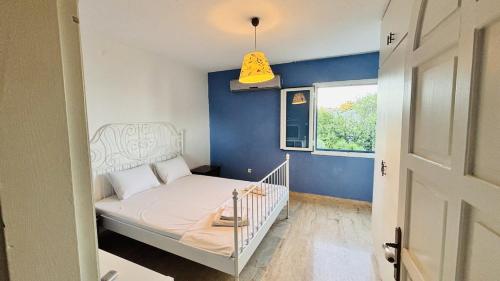 a small bedroom with a bed and a blue wall at Çeşme Seaside House in Çeşme