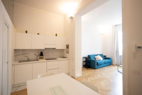 a kitchen with white cabinets and a blue couch at SINONDA Luxury Apartment in Maiori