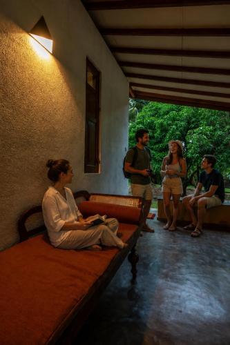 a woman sitting on a bed in a room with people at WildEscape, Yala Blocks 3, 4 & 5 in Buttala