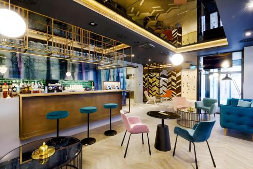 a lobby with a bar with chairs and tables at KVi Hotel Budapest - the smart hotel in Budapest