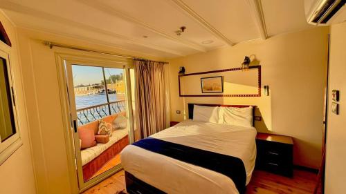 a hotel room with a bed and a balcony at Dahabiya Queen Tyi II in Luxor