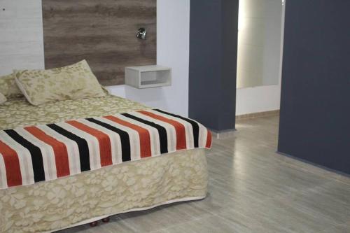 1 dormitorio con 1 cama con manta a rayas en Talu Apart Hotel en San Rafael