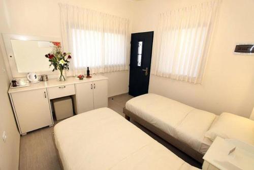 a small room with two beds and a mirror at Achuza Bamarom in Safed