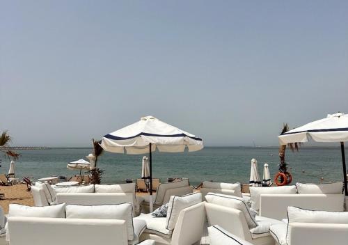a group of white chairs and umbrellas on a beach at Paradise Inn Beach Resort in Alexandria