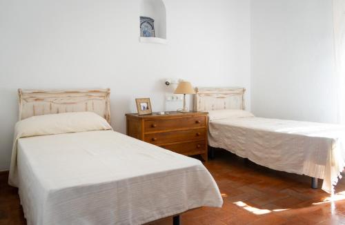 two beds in a room with white sheets and a dresser at Cortijo El Solano in Antequera