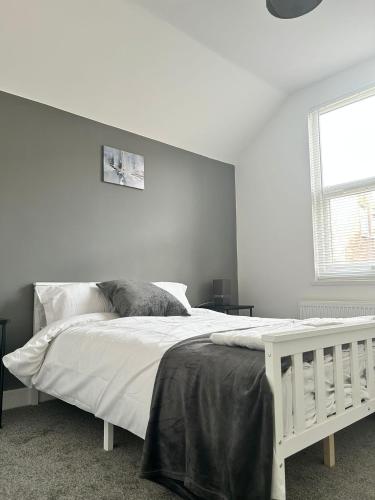 a white bedroom with a white bed and a window at The Lenton House in Nottingham