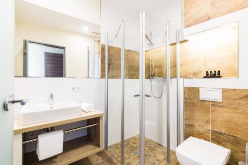 
a bathroom with a sink, toilet and shower at SKY Hotel Cloppenburg in Cloppenburg
