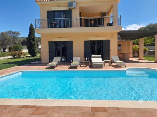 a villa with a swimming pool in front of a house at Private Pool Villas in Svoronata