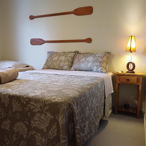 a bedroom with a bed and a table with a lamp at Kite House Lençóis in Santo Amaro