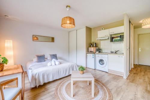 a bedroom with a bed and a table and a kitchen at Jardins de Flore in Mérignac