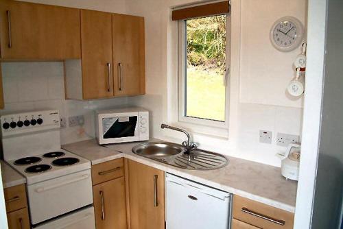 a kitchen with a sink and a stove and a window at Lochead Chalet 2 in Lochgilphead
