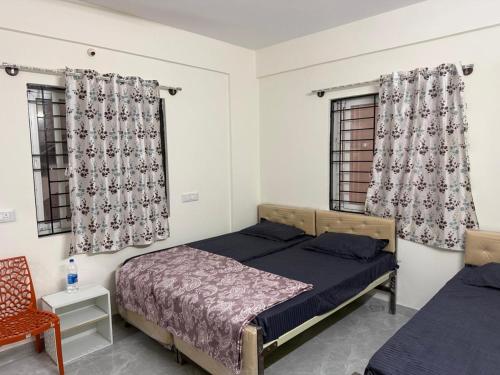 a bedroom with two beds and two windows at VR Colive in Kammasandra