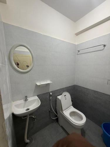 a bathroom with a toilet and a sink and a mirror at VR Colive in Kammasandra