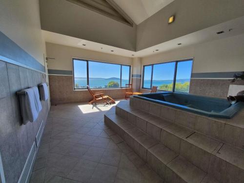 a large bathroom with a large tub and large windows at Novotel Rotorua Lakeside in Rotorua