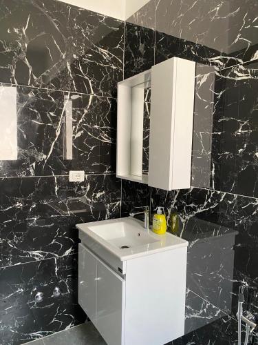 un bagno con lavandino bianco e pareti in marmo nero di Arval Rooms a Vlorë