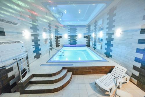 a swimming pool in a room with stairs and a tub at Hotel Jasmin All Inclusive in Truskavets