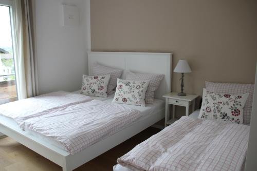 Habitación blanca con 2 camas y almohadas en Ferienwohnung Ammersee by paul apartments, en Herrsching am Ammersee