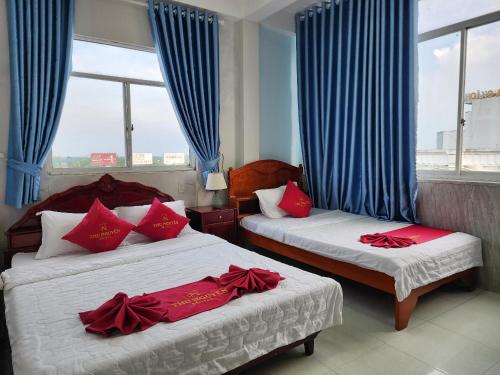two beds in a room with blue curtains and red pillows at KHÁCH SẠN THU NGUYỄN - ngay BẾN NINH KIỀU, CHỢ ĐÊM in Can Tho