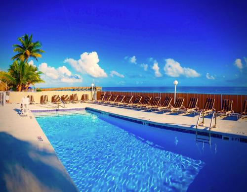 uma piscina com cadeiras e o oceano ao fundo em Key Colony Beach Motel em Marathon