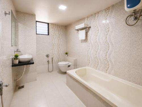 a bathroom with a tub and a toilet and a sink at Hotel Apollo Sp Ring Road Odhav Ahemdabad in Ahmedabad