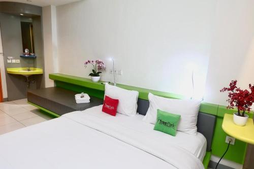 a bedroom with a white bed with red and green pillows at TreePark Hotel Jakarta Airport in Tangerang