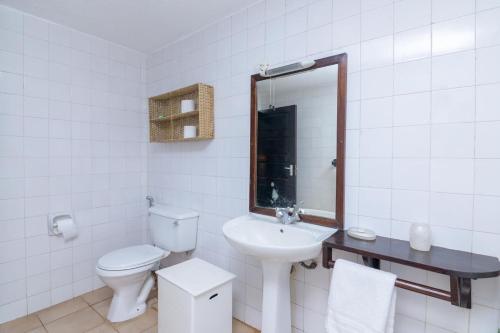 a white bathroom with a toilet and a sink at Driftwood Beach Malindi Palace in Malindi