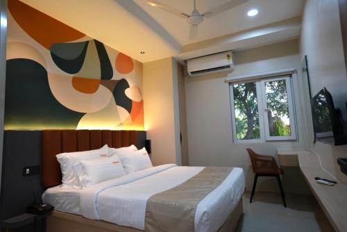 a bedroom with a bed with a painting on the wall at TheCloud Hotel in Nizāmābād