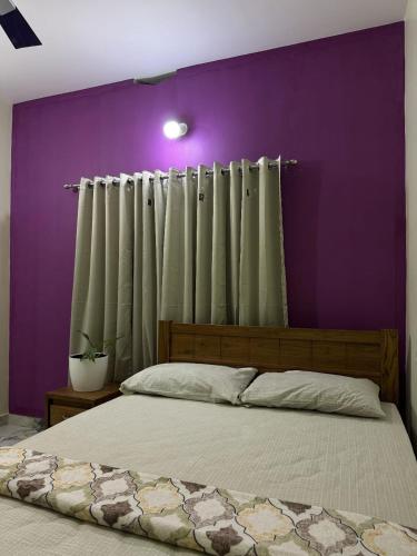 a bedroom with a bed with a purple wall at Mountain pride homestay in Meppādi