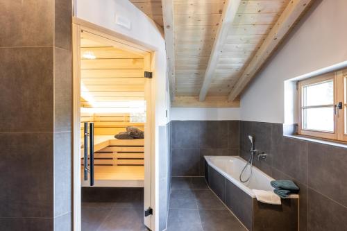 a bathroom with a tub and a shower with a window at Waldchalets & Ferienwohnungen Allgäu in Burgberg