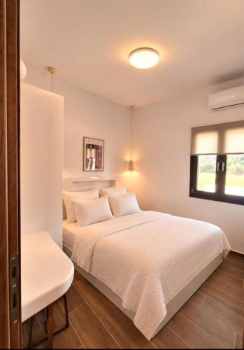a bedroom with a white bed and a window at Smovolo houses 1 in Agios Sostis