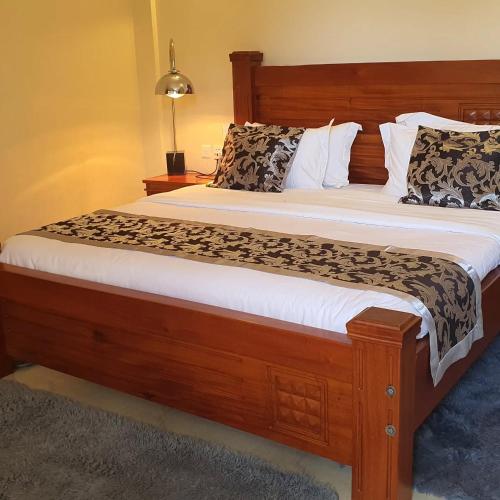 a bedroom with a large wooden bed with white sheets at OLOIRIEN HOTEL & RESORT in Narok