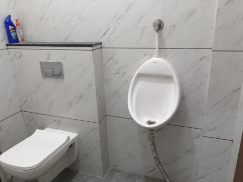 a bathroom with a white urinal and a toilet at Raghav Sarkar Parisar in Indore