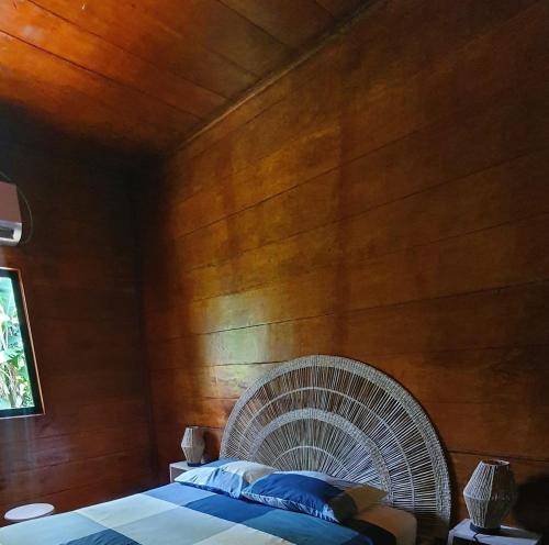 a bedroom with a wooden wall with a bed and a fan at Casa do Príncipe in Santo António