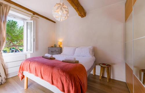 a bedroom with a bed with a red blanket and a window at Apt Libelule in Tourrettes-sur-Loup