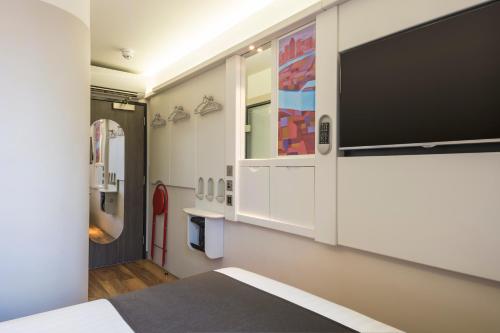 a bedroom with a large flat screen tv on the wall at Point A Hotel London Shoreditch in London