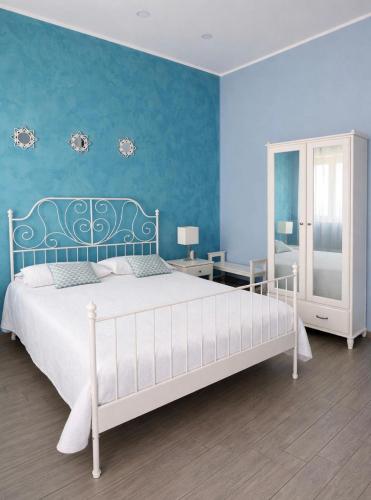 a bedroom with a white bed and a blue wall at Ciao Ciao Rooms in Letojanni