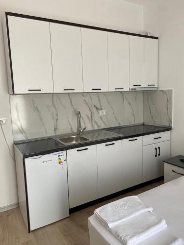 una cucina bianca con lavello e mobili bianchi di Arval Rooms a Vlorë