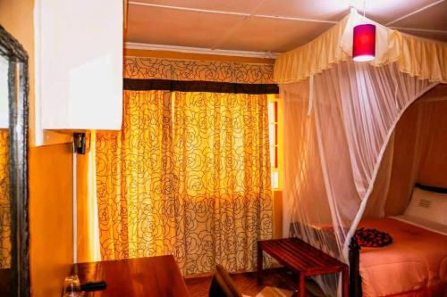 a bedroom with a bed and a curtain and a table at Pine Breeze Getaway Lukenya in Athi River