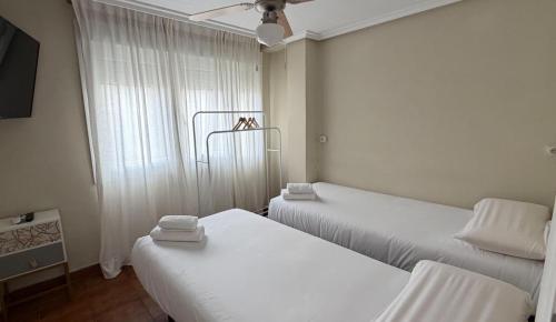 a room with two beds and a window at Hostal Entre Puertas in Aranda de Duero
