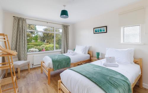 two beds in a room with a window at Westway - 3 Bed Coastal Bungalow with Large Garden Steps from Colwell Bay Beach in Freshwater