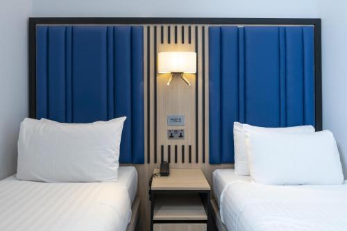 two beds in a hotel room with blue walls at Best Western Victoria Palace in London