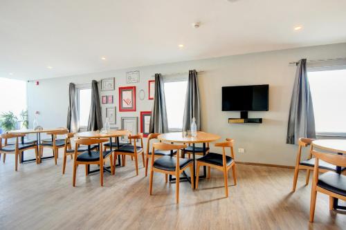 a dining room with tables and chairs and a flat screen tv at Hotel O Crowninn in Faridabad