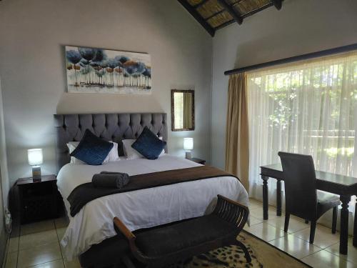 a bedroom with a bed with a desk and a chair at Selati 103 Guest Cottages in Malelane
