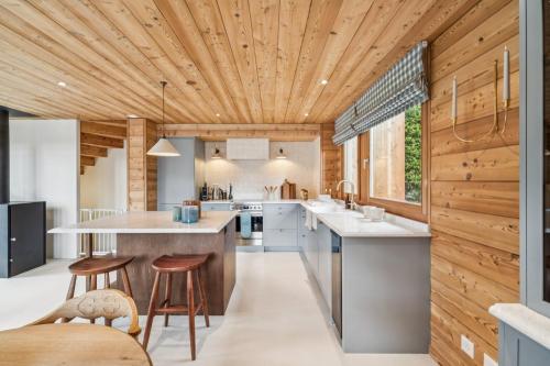 a kitchen with wooden ceilings and a large island with bar stools at Chalet SkyLodge by Mrs Miggins in Grimentz