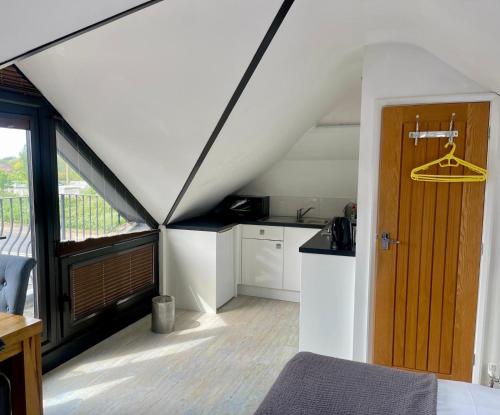 a room with a kitchen and a door in a attic at Hunters Hide Apt in Littlehampton