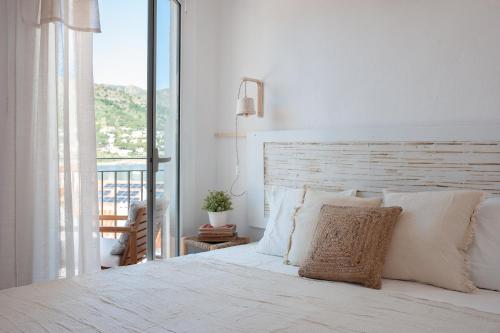 a white bedroom with a bed and a balcony at Hostal Boutique Es Grop in Port de la Selva
