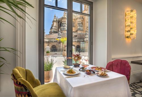 a table with food on it in a room with a window at Gran Hotel Claridge Granada - Preferred Hotels & Resorts in Granada