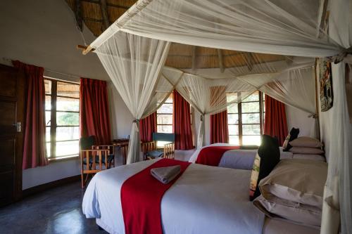a bedroom with two beds and red curtains at Hlane Royal National Park in Simunye